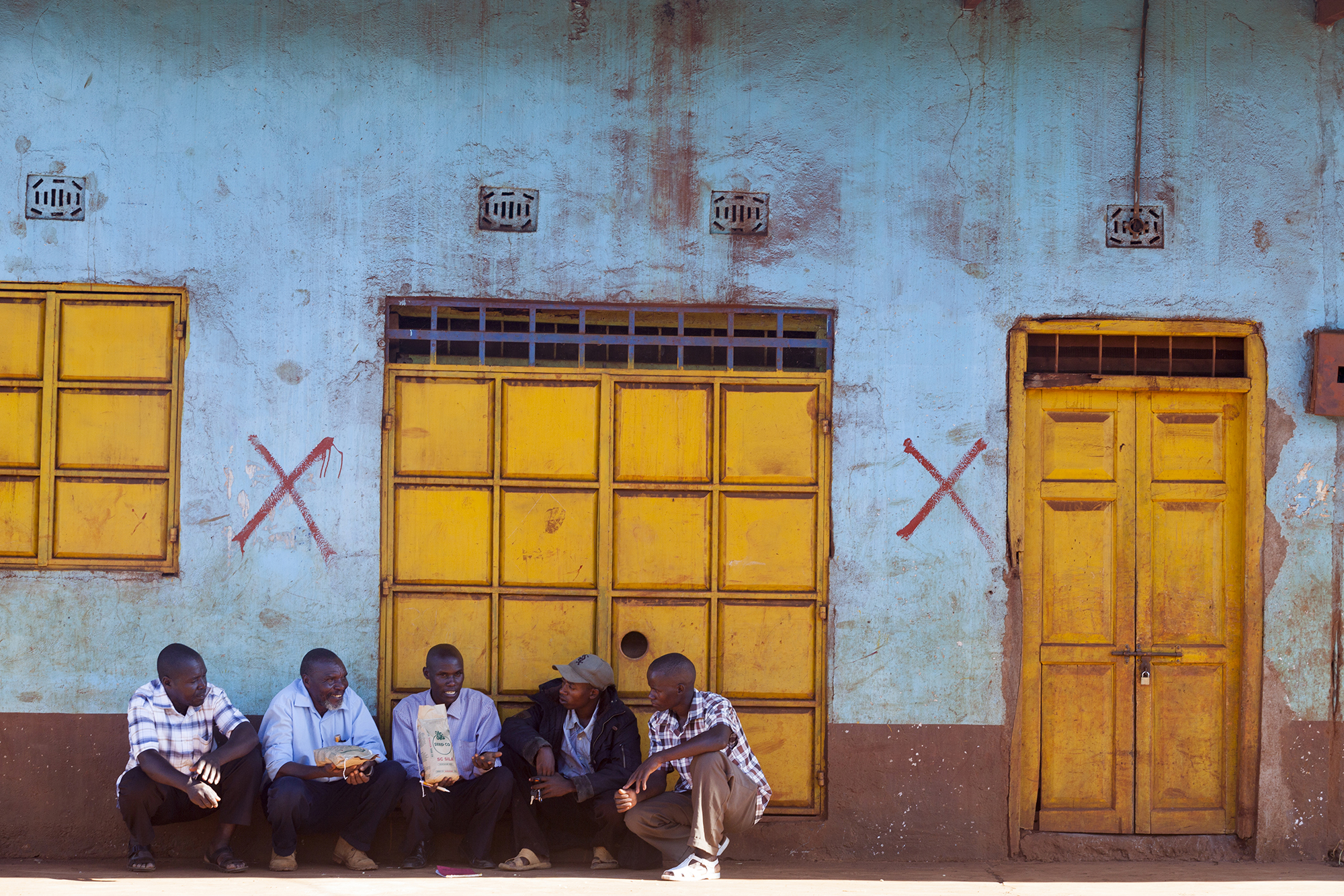 2133 Five Men Sitting Outside Building Sorghum Pioneer Root Capital Stuart Freedman