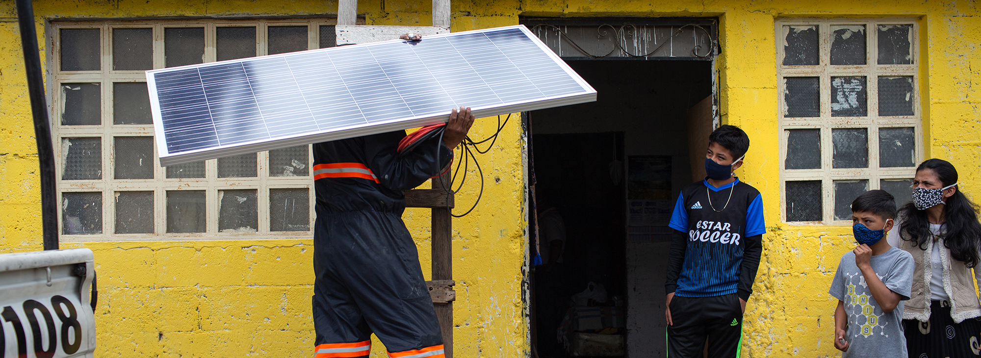 2125 Man On Ladder Holding Solar Panel Alterna Energica Solar Copyright James Rodríguez Panos Banner