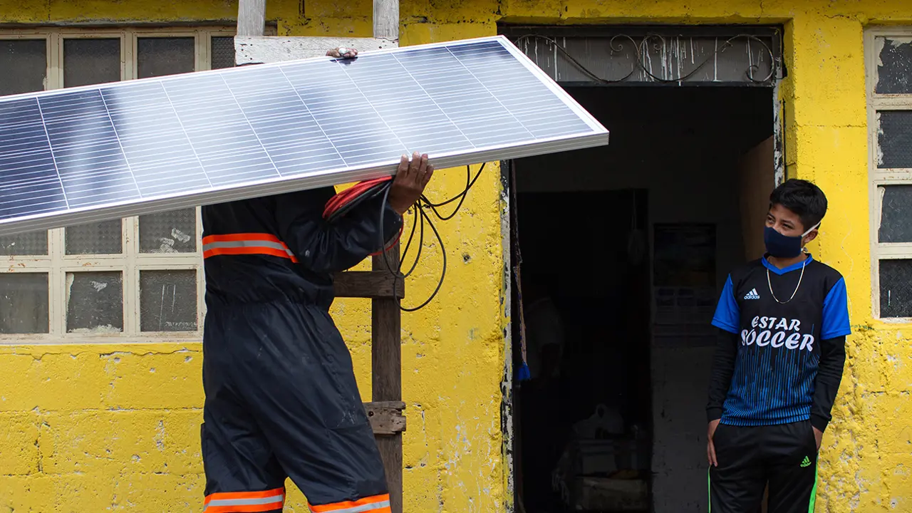 2125 Man On Ladder Holding Solar Panel Alterna Energica Solar Copyright James Rodríguez Panos Banner