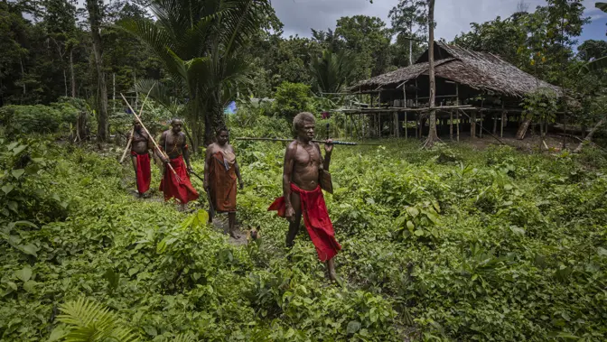 4 tribesmen walking through a field
